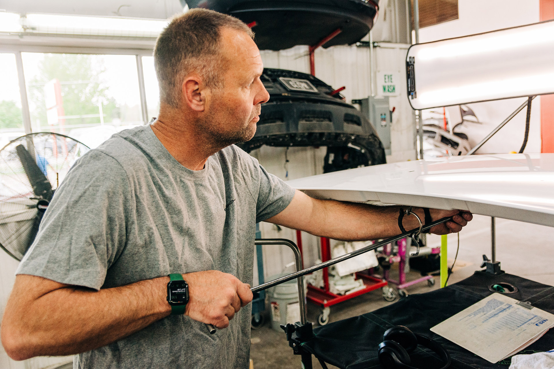 Paintless dent repair near me - A technician performs paintless dent repair operations on a vehicle hood at the Prestige Imports Collision Center in Lakewood, CO