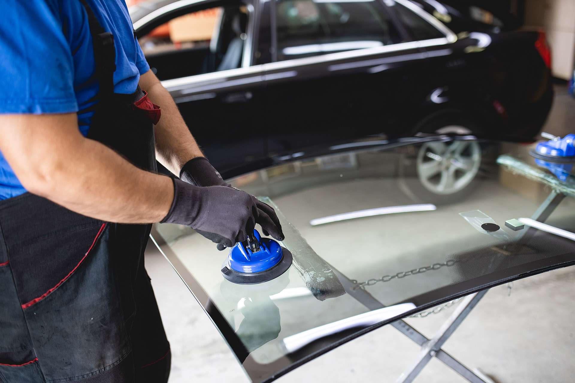 Technician preparing windshield glass for installation in a vehicle.