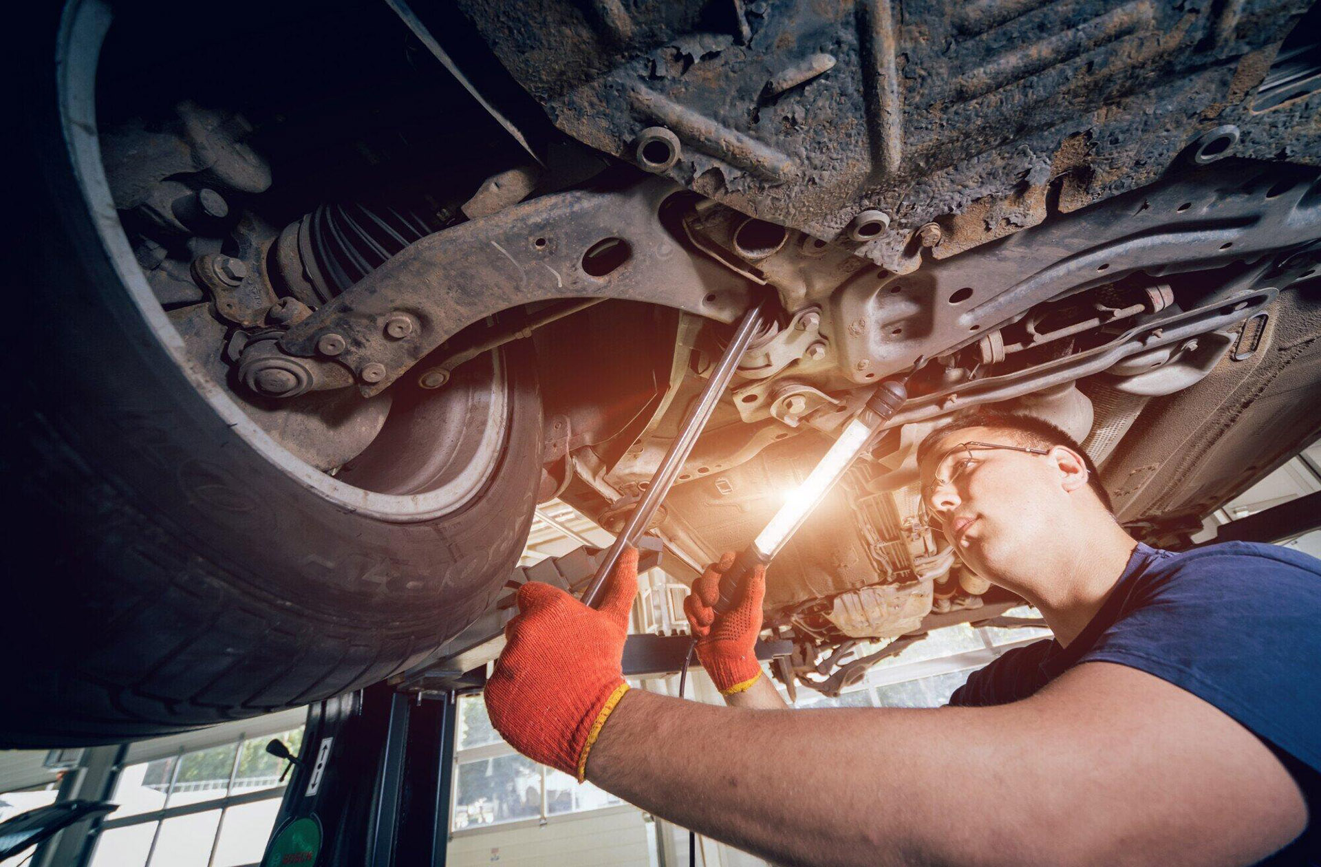 Collision Center Technician examining a vehicle suspension for damage.